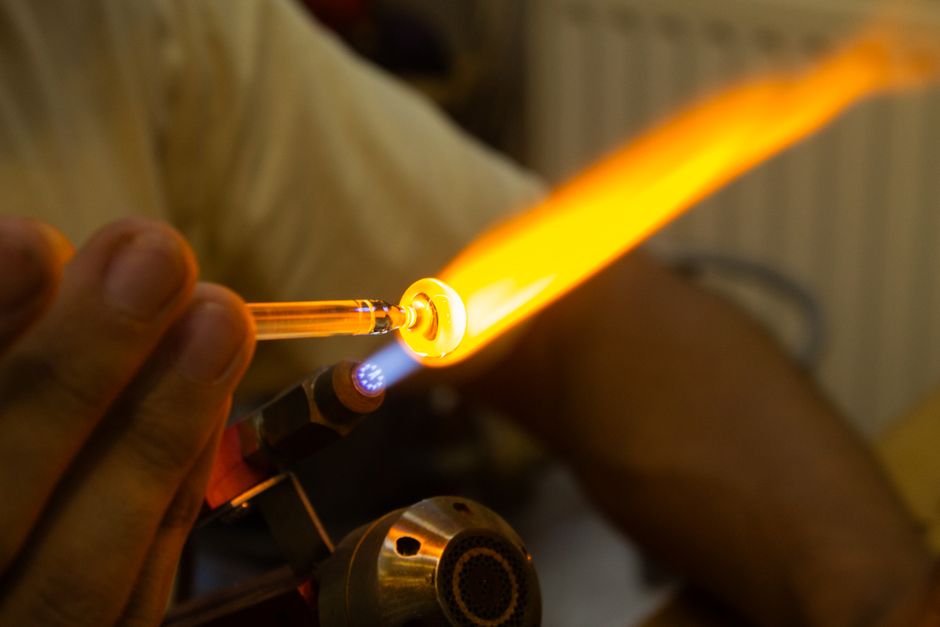 Person shaping glass with a bright torch