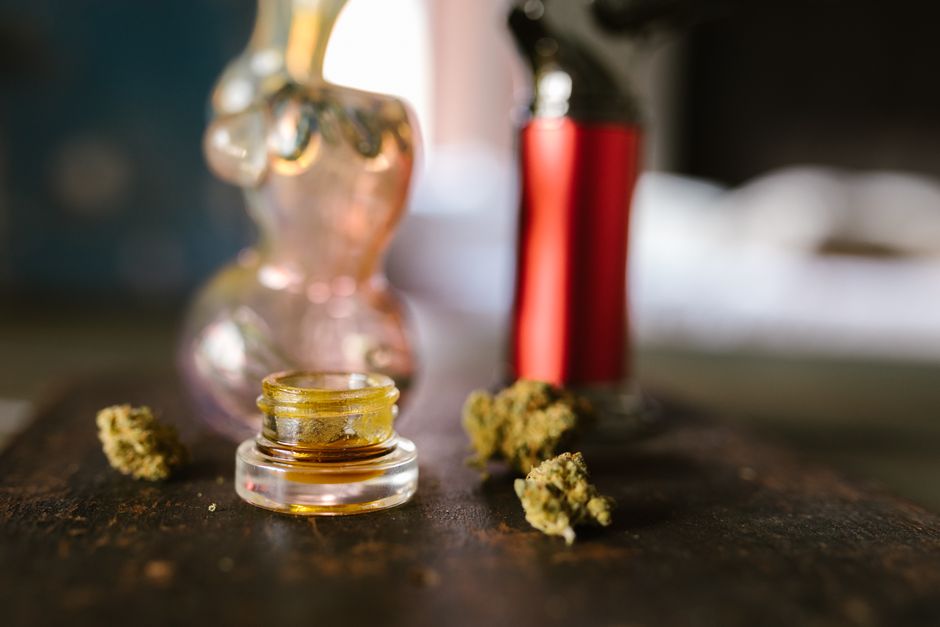 Cannabis buds jar and glass pipe on table